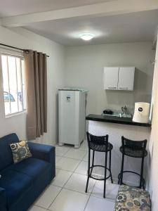 a living room with a couch and a kitchen with a refrigerator at Apartamento Premium Grand Luxo in Fortaleza