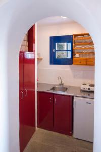 a kitchen with red cabinets and a sink at Marketos Windmill and Houses in Tripití