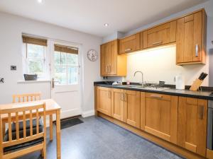 a kitchen with wooden cabinets and a table and a sink at Poldark Cottage in Charlestown