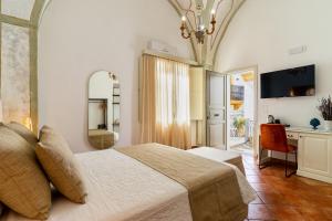 a bedroom with a bed and a desk and a mirror at Corte Patitari - by Patitari Suites in Gallipoli