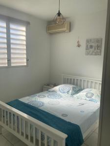 um quarto com uma cama com um edredão azul e branco em Martinique trois ilets face à la mer em Les Trois-Îlets