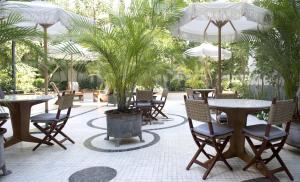 a patio with tables and chairs and palm trees at The Norman Tel Aviv in Tel Aviv
