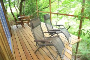 2 chaises et une table sur une terrasse dans l'établissement Cabane au cœur de la forêt des Landes de Gascogne, à Belin-Beliet