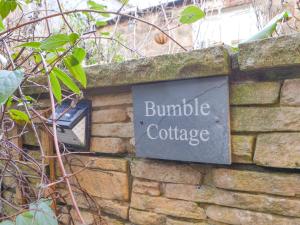 a brick wall with a sign that reads bubble cottage at Bumble Cottage in Cockermouth