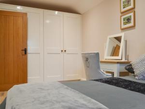 a bedroom with a bed and a desk with a chair at Bumble Cottage in Cockermouth