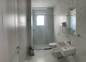 a white bathroom with a toilet and a sink at Suite Hotel in Shëngjin
