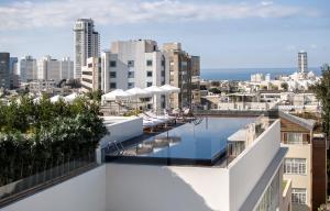 a swimming pool on top of a building with a city at The Norman Tel Aviv in Tel Aviv