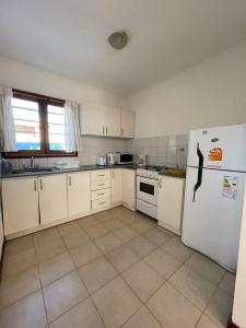 a kitchen with white cabinets and a white refrigerator at Casa Storni in Mar del Plata