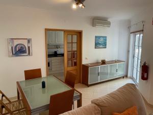 a living room with a glass table and a kitchen at A Casa do Carlos in Vila Nova de Cacela