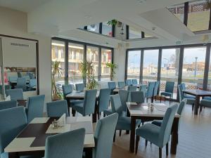 a dining room with tables and chairs and windows at C&C Mamaia Studio in Mamaia