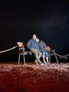 a man and woman sitting on a bench at night at Quite bedouin life in Wadi Rum
