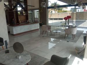 eine Lobby mit einem Tisch, Stühlen und einer Theke in der Unterkunft Departamento en Puebla (en torre Artema- zona Angelópolis) in Puebla
