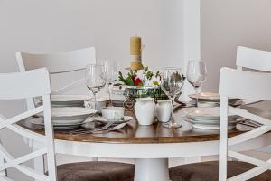 uma mesa de jantar branca com pratos e copos de vinho em ARI Central Green Apartment em Arad