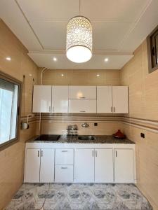 Appartement calme à Fès في فاس: مطبخ مع دواليب بيضاء ومغسلة