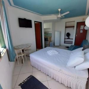 - une chambre avec un lit blanc et une table dans l'établissement Arraial Flats, à Arraial do Cabo
