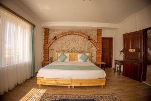 een slaapkamer met een groot bed met een bakstenen muur bij Soleado Cappadocia Hotel in Uchisar