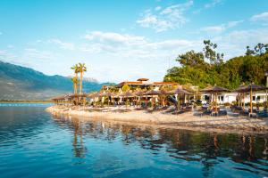 a beach with umbrellas and chairs and the water at Aquata Apartments in Tivat