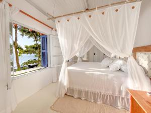 1 dormitorio con cama y ventana en BlowShow Casa I, en Ilhabela