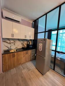 a kitchen with a stainless steel refrigerator and large windows at Apartment Merabi in Batumi