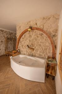 a bath tub in a room with a stone wall at Soleado Cappadocia Hotel in Uchisar