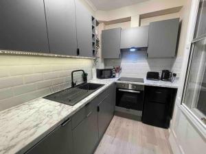 a small kitchen with a sink and a stove at Newly refurbished, central apartment with permit parking in Bath