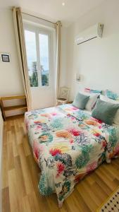 ein Schlafzimmer mit einem Bett mit einer bunten Bettdecke in der Unterkunft Hôtel La Villa Patricia - Charme et Tradition in Villefranche-sur-Mer