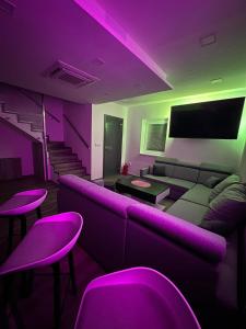 Zimmer mit lilafarbener Beleuchtung, Sofa und Hocker in der Unterkunft Magika in Uherský Brod