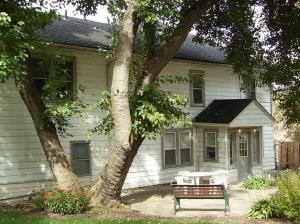 a bench in front of a house with a tree at Casual Living Extended Stay Hotels in Algonquin