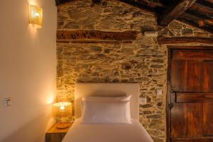 a bed in a room with a stone wall at Casa Grande do Soxal in Cesuras