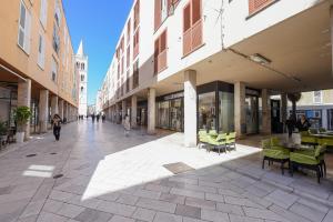 eine leere Straße mit Tischen, Stühlen und Gebäuden in der Unterkunft Aura Exclusive Apartment & Room in Zadar
