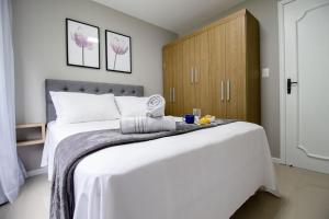 1 dormitorio con 1 cama blanca grande y armario de madera en BRC71 - Quadra Mar, Lindo Espaço, Churrasq, Sacada, en Balneário Camboriú