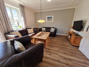 a living room with leather couches and a coffee table at Ferienhaus Ellen, EG Whg in Utersum