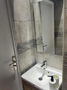 uma casa de banho com um lavatório e um espelho em Appartement confortable Olympic games JO24 em Aubervilliers