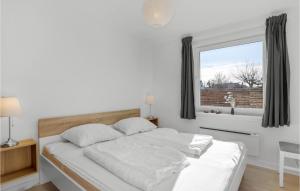Una cama blanca en una habitación con ventana. en 2 Bedroom Stunning Home In Svaneke, en Svaneke