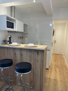 uma cozinha com um balcão e dois bancos num bar em Appartement confortable Olympic games JO24 em Aubervilliers