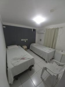 a hospital room with two beds and a chair at Hotel Aurora in Alagoinhas