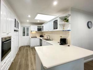 a kitchen with white cabinets and a white counter top at Penlink Lodge - Base To Explore Mornington Peninsula in Langwarrin