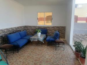 une terrasse avec des canapés bleus, une table et des chaises dans l'établissement Huge Cozy Apartment, à Larache