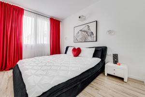 a bedroom with a large bed with red curtains at ARI Cinema Apartament in Arad