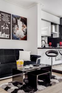 uma sala de estar com um sofá preto e uma mesa em ARI Cinema Apartament em Arad