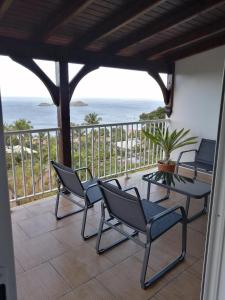 a balcony with chairs and a table and the ocean at Duplex Rose Porcelaine - Vue Mer- Malendure in Bouillante
