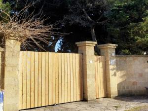 una recinzione di legno con due posti e un cancello di Villa Memia a Lendinuso