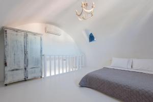 una camera da letto bianca con un letto e un lampadario di Red Cliff Santorini Villa - Volcano View & Jacuzzi ad Akrotírion Altre 28 foto