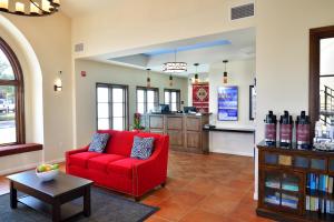 ein Wohnzimmer mit einem roten Sofa und einem Tisch in der Unterkunft Lamplighter Inn & Suites at SDSU in San Diego