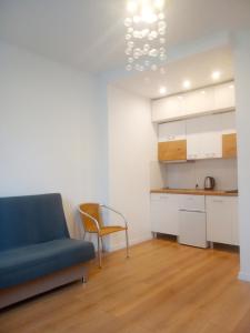 a living room with a blue couch and a kitchen at Mieszkanie ul Przędzalniana in Białystok