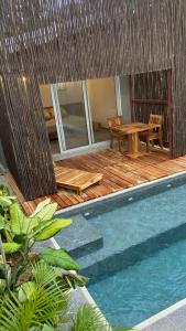 una terraza de madera con mesa y mesa de picnic junto a la piscina en Bahía Santamaría, en Moñitos