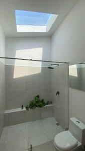 uma casa de banho com um chuveiro, um WC e uma janela. em Bahía Santamaría em Moñitos