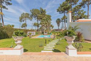 a garden with two urns and a swimming pool at Villa Whiteloft Pool Spa Lounge in Corroios