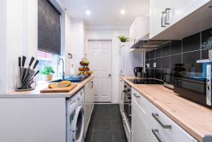 una cucina con armadi bianchi e piano di lavoro di Kingsway House a Coventry