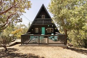 une maison noire avec une porte verte dans les bois dans l'établissement Dog Friendly A-Frame Hot Tub Nature Views, à Idyllwild